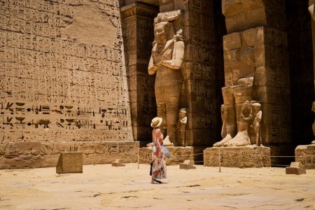 Closeup shot of a female standing in front of a Medinet Habu temple in Egypt