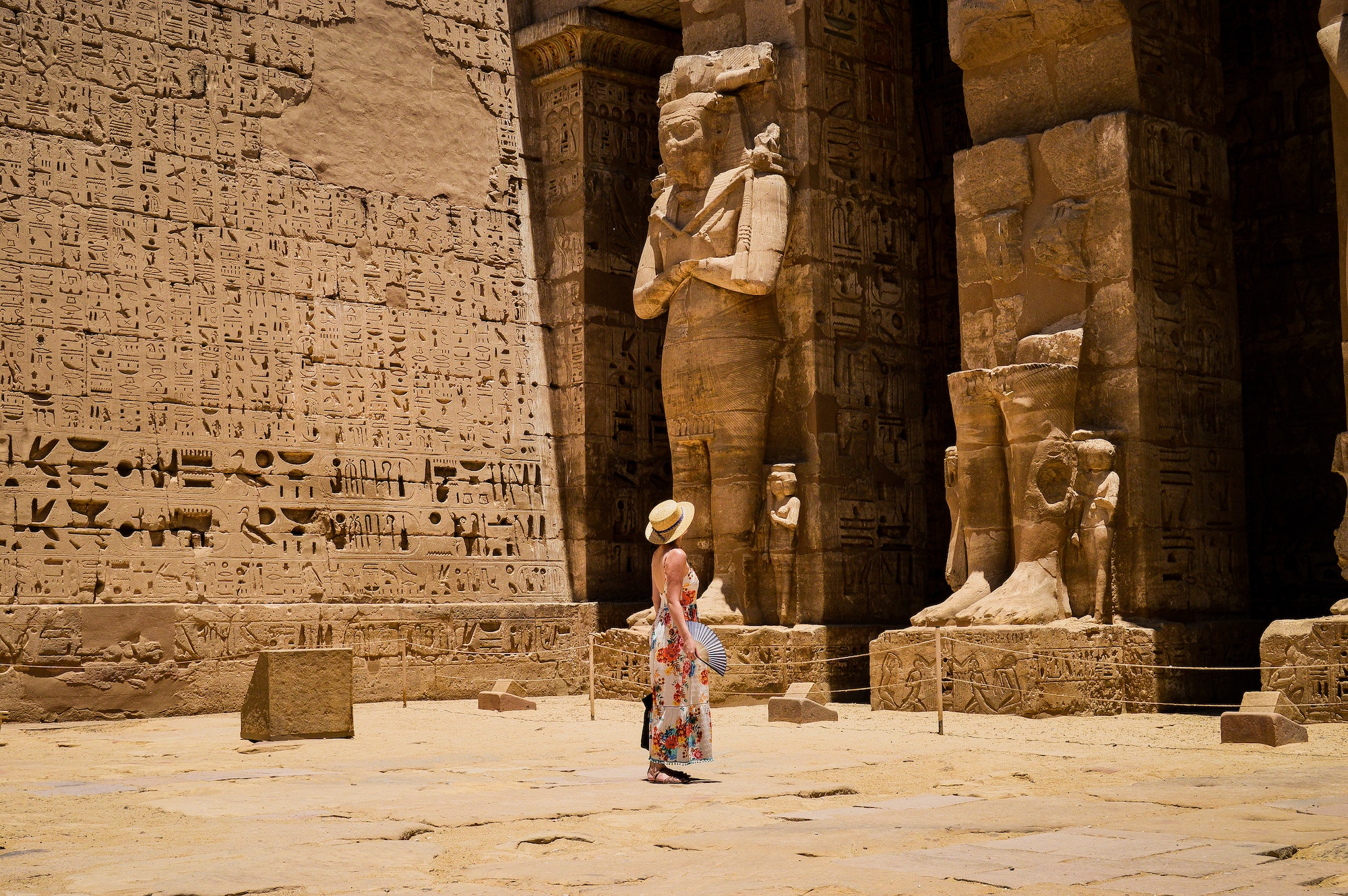 Closeup shot of a female standing in front of a Medinet Habu temple in Egypt