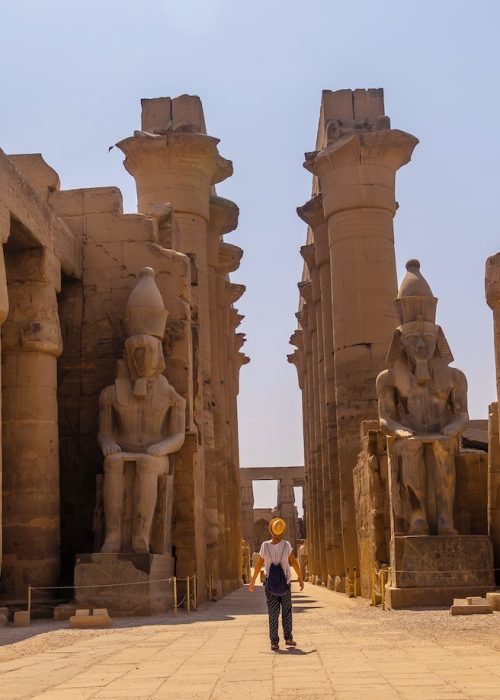 Woman tourist with a hat visiting the Egyptian Temple of Luxor and its beautiful columns