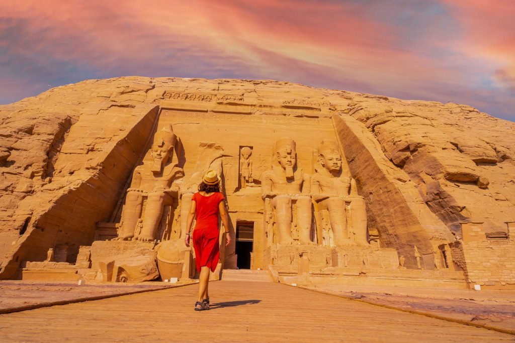 A traveler walking toward the Great Temple of Abu Simbel at sunset