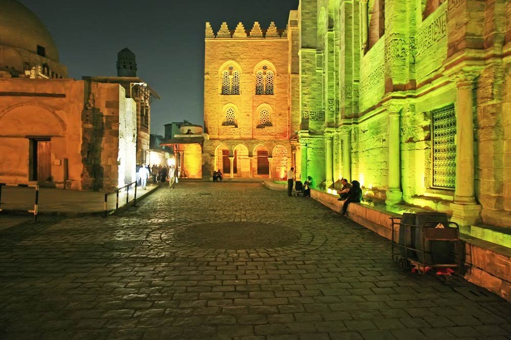 A lit-up historic street of Islamic Cairo at night, where koshari shops stay busy