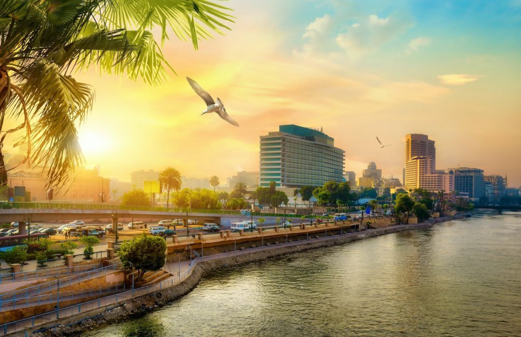 The Nile corniche in Cairo at sunset with palm trees and riverside buildings