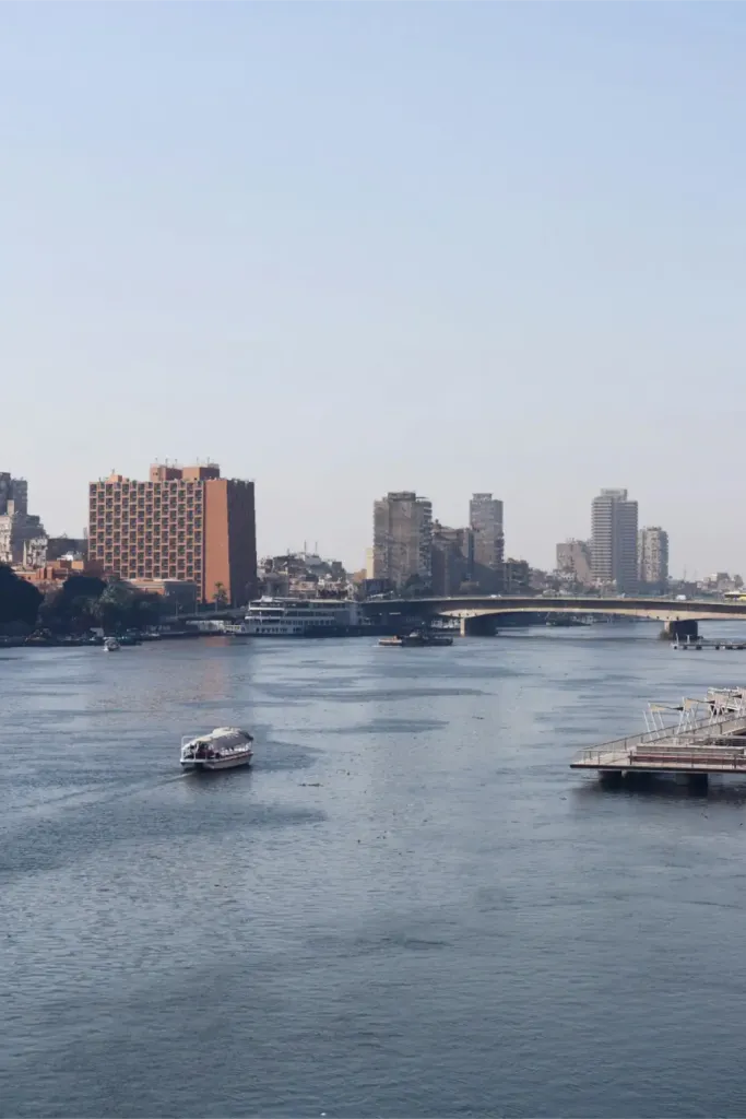 A small boat on the Nile in Cairo with a bridge and high-rise buildings behind