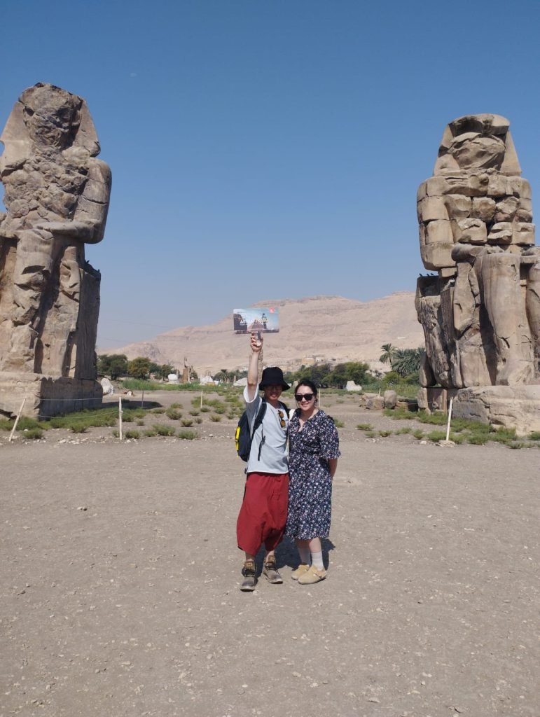 Two travelers standing between the Colossi of Memnon