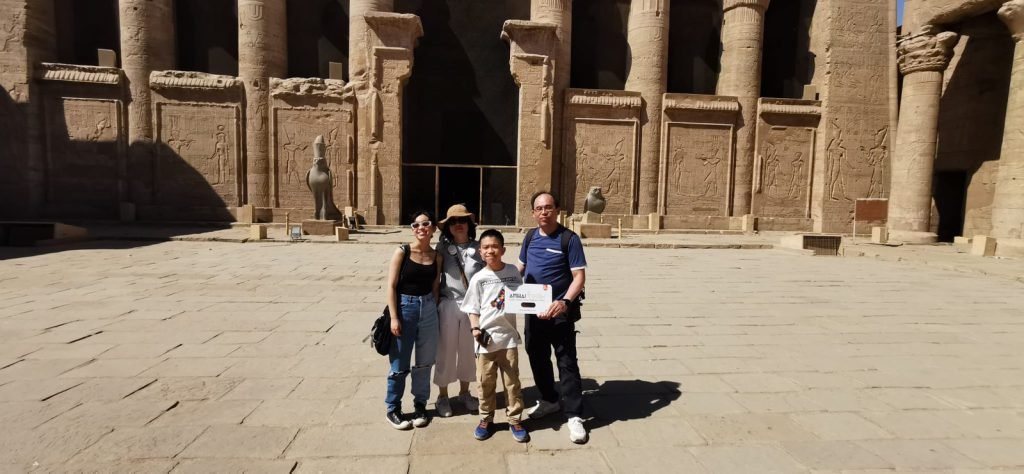 A family of travelers in front of the hypostyle hall of the Edfu temple
