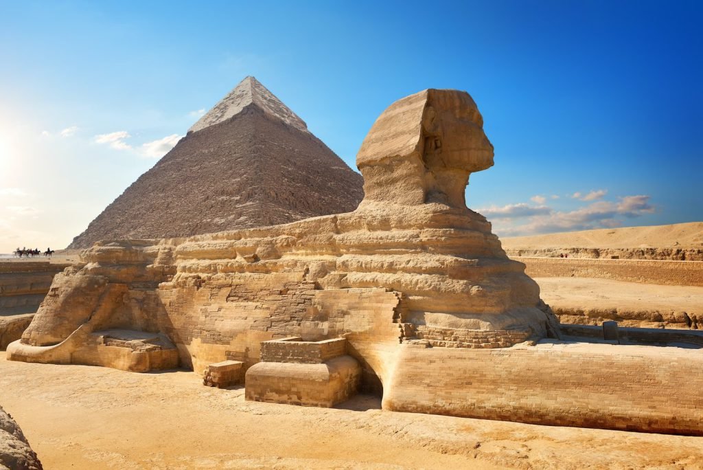 The Great Sphinx in front of the Pyramid of Khafre under a clear blue sky