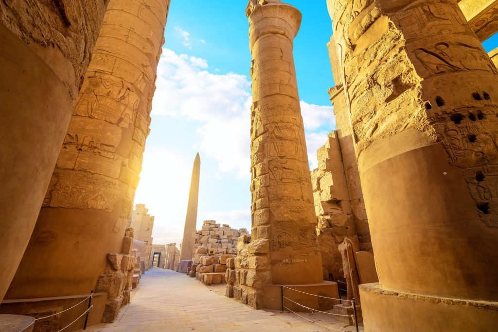 Sunlit columns of Karnak with an obelisk in the distance