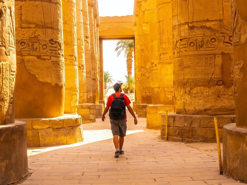 A traveler walking between the carved columns of Karnak Temple