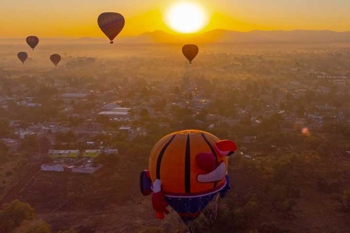 A balloon drifting over Luxor as the sun rises