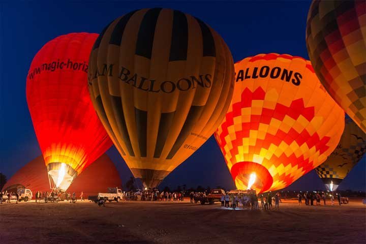 Hot-air balloons lit up by their burners before dawn
