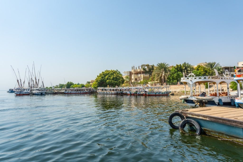 Boats moored along the green riverbank of the Nile in Luxor