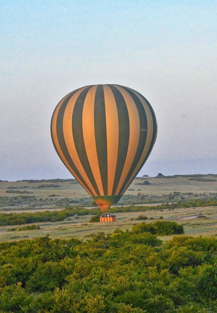 A striped hot-air balloon above farmland near Luxor
