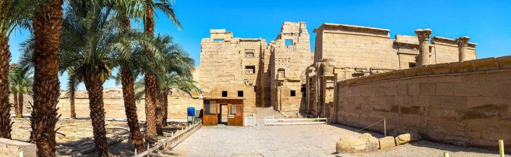 The fortified gate of Medinet Habu framed by palm trees