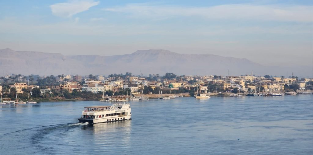 A Nile cruise ship sailing past Luxor with the Theban hills behind