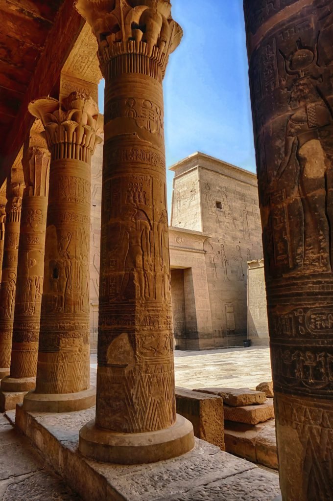 Carved columns in the Temple of Philae with a pylon behind