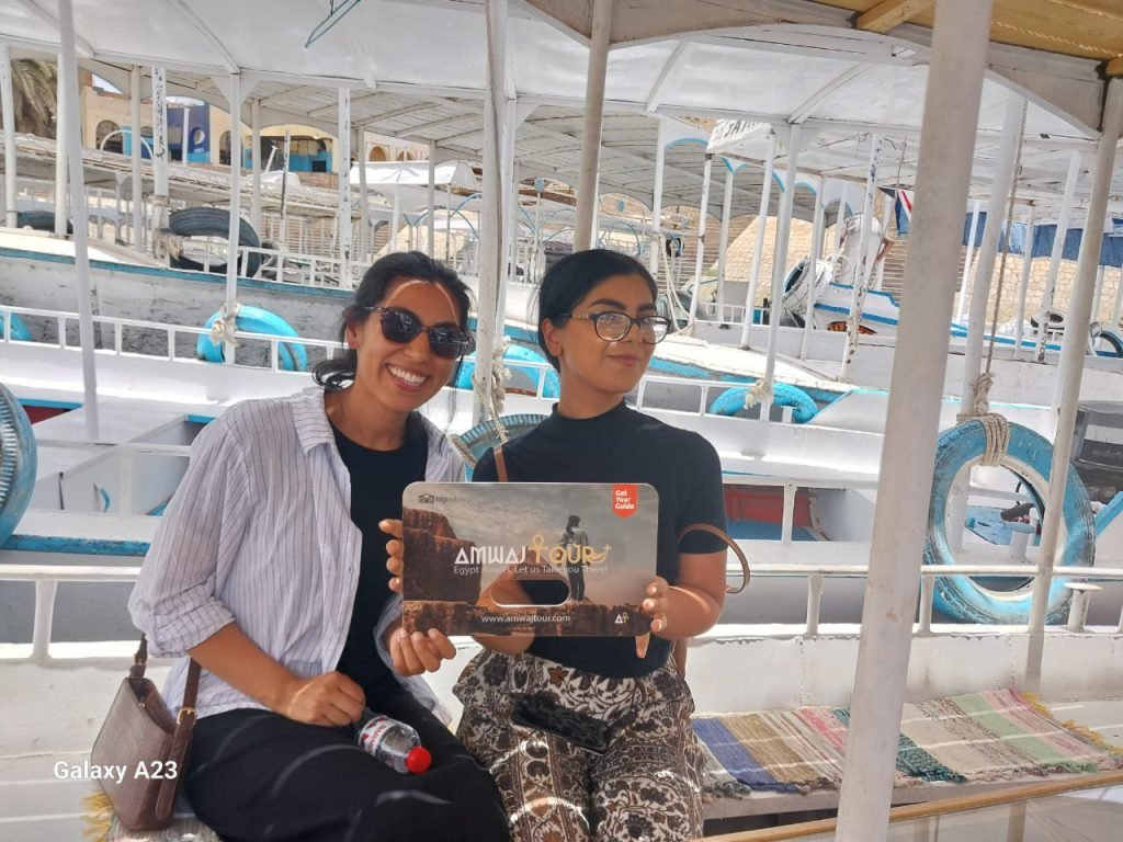 Two travelers with an Amwaj Tour sign on a motorboat on the Nile in Aswan