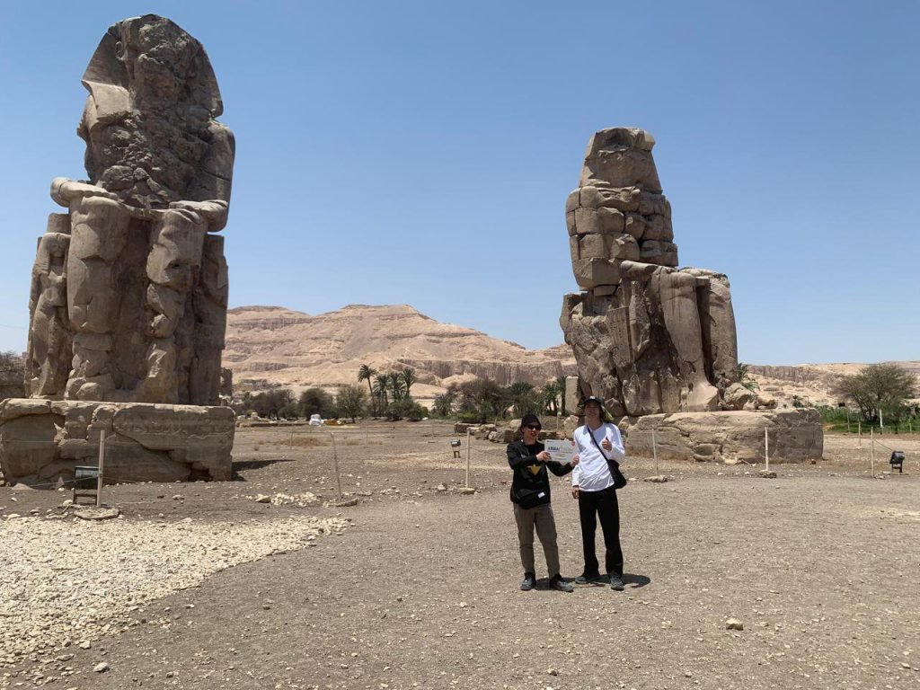 Two travelers between the twin Colossi of Memnon on Luxor's West Bank