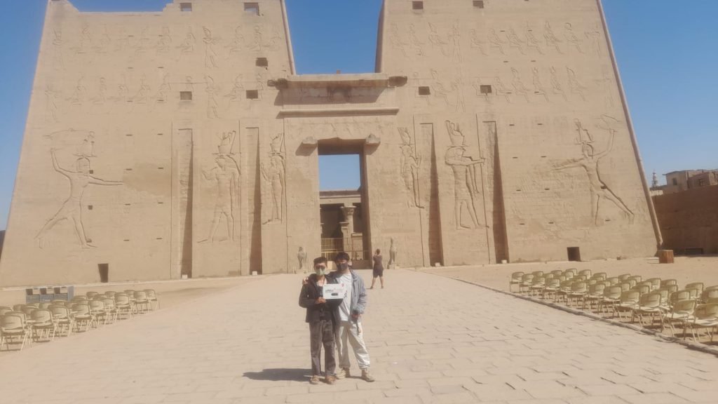 Two travelers in front of the great pylon of Edfu Temple