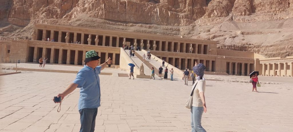 A couple with arms open wide in front of the Temple of Hatshepsut
