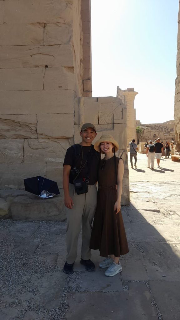 A couple standing by an ancient temple wall in Luxor