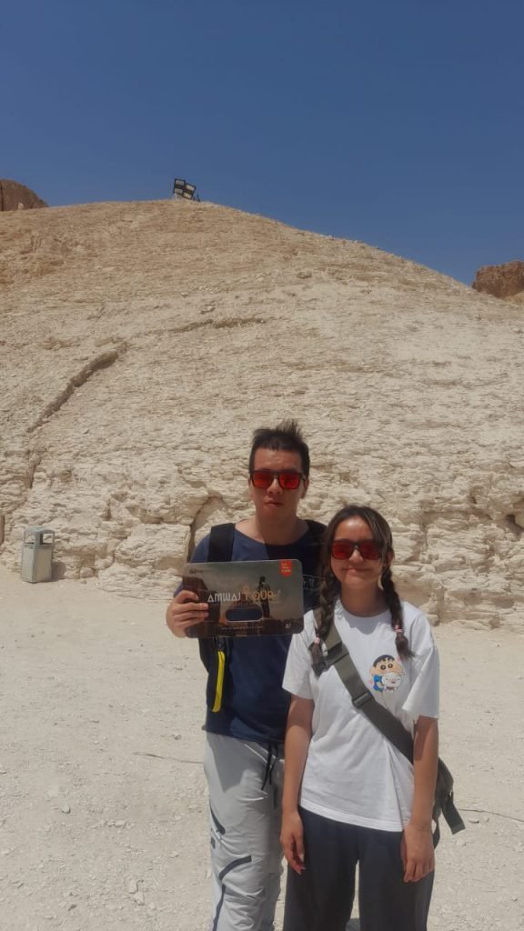 A couple with an Amwaj Tour photo card in the Valley of the Kings