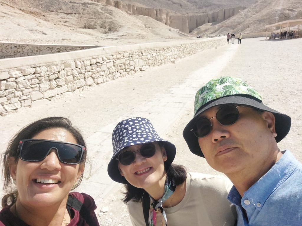Three smiling travelers taking a selfie on the path in the Valley of the Kings