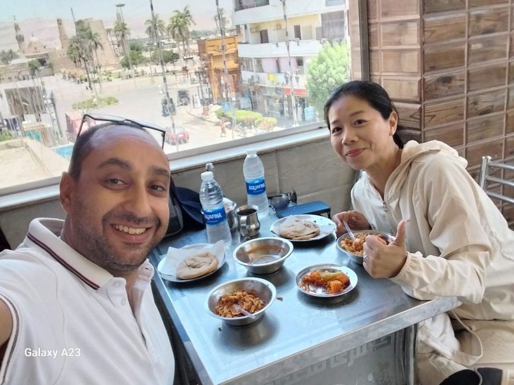 An Amwaj Tour guide and a traveler sharing a traditional Egyptian meal with a view over Luxor