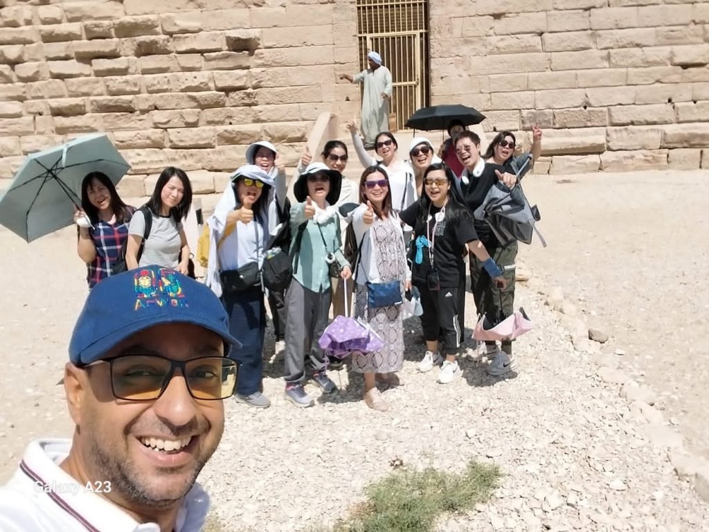 An Amwaj Tour guide taking a selfie with a large group of travelers at an ancient temple